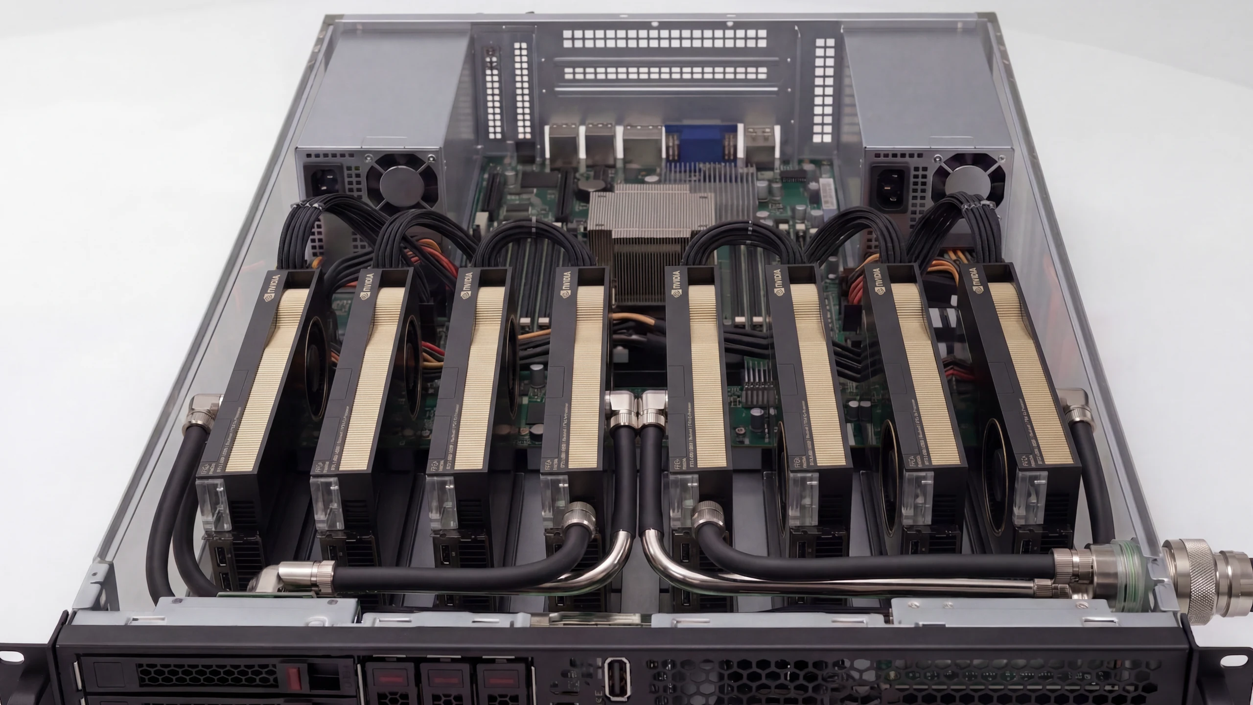 An Allodial Furnace with its lid off: eight NVIDIA accelerators seated in a row across the chassis, liquid-cooling lines running between them to a quick-disconnect coupling at the rear, twin power supplies and the board visible behind, hot-swap drive bays across the front.